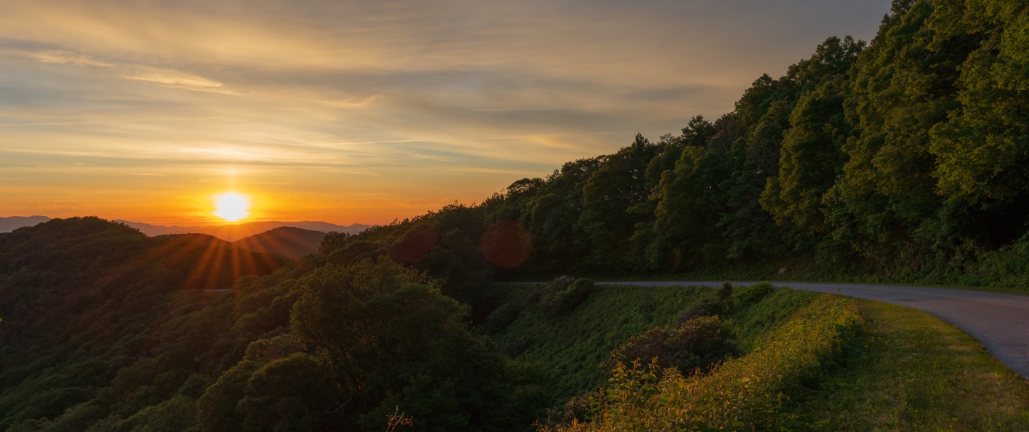 The sun peeks above the mountain along the Blue Ridge Parkway, one of the best places to catch fall foliage in Asheville.