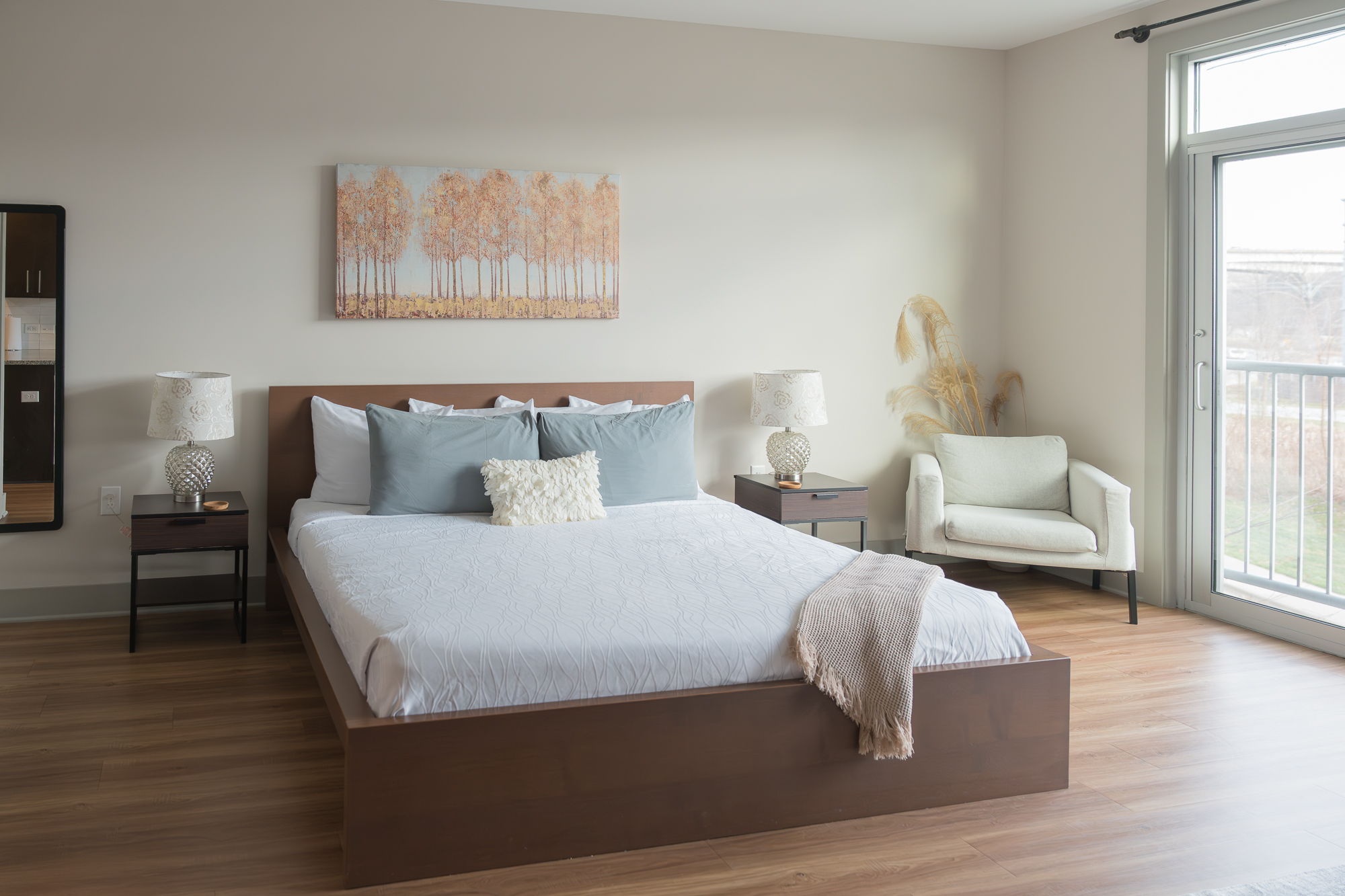 A neatly made bed with pillows and a chair in a room with a window.
