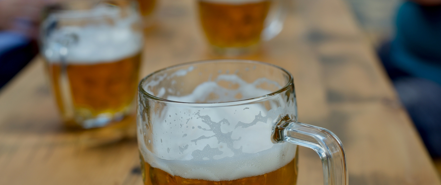 a wooden table with multiple steins of draft beer