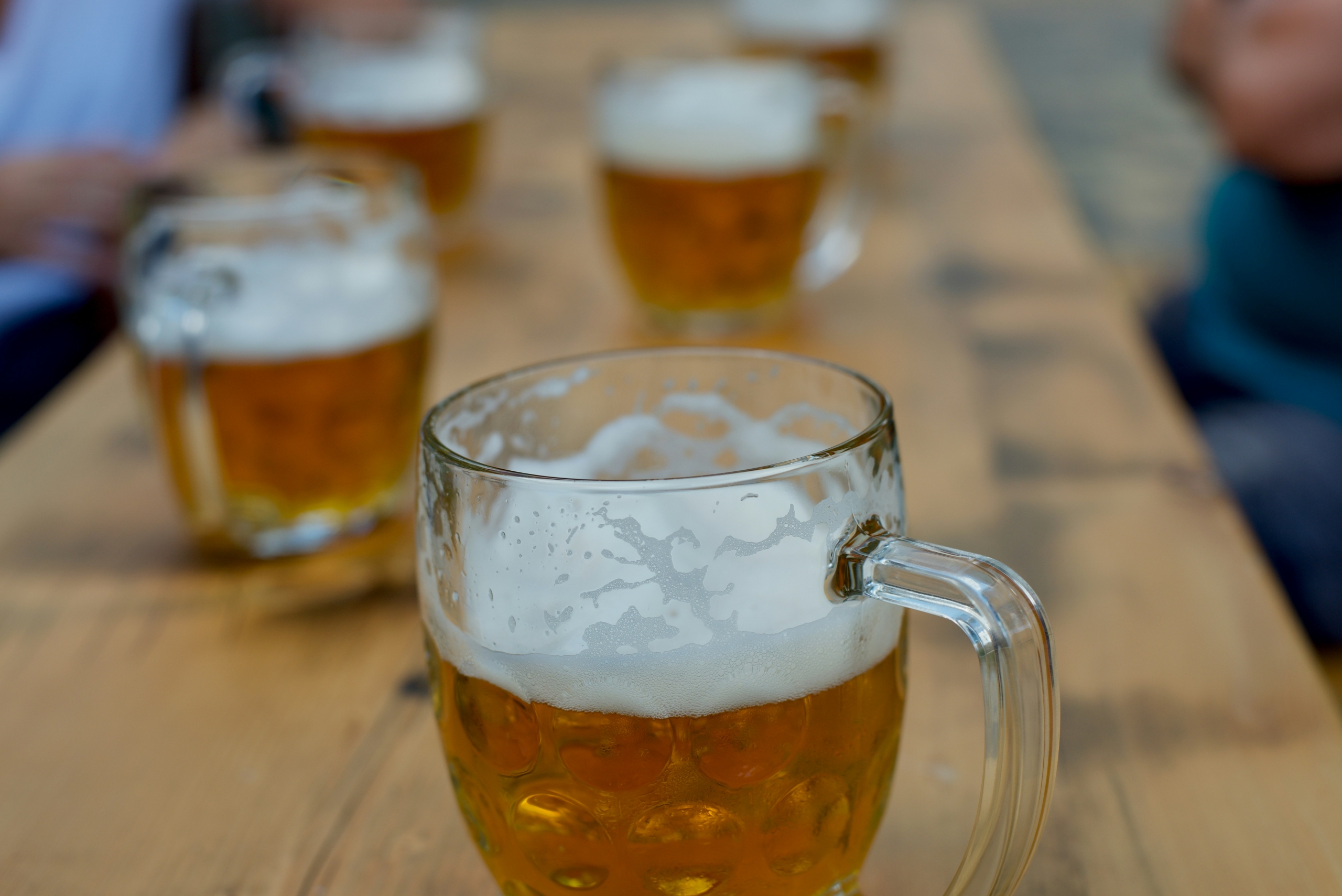 a wooden table with multiple steins of draft beer