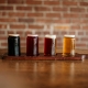 a flight of draft beers against a brick wall