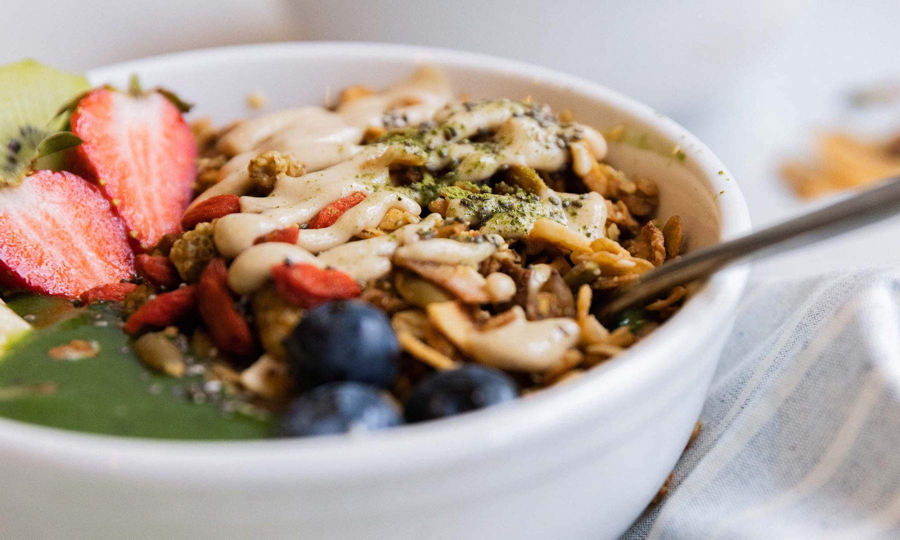 A close-up of a bowl of granola with fruit and nuts.