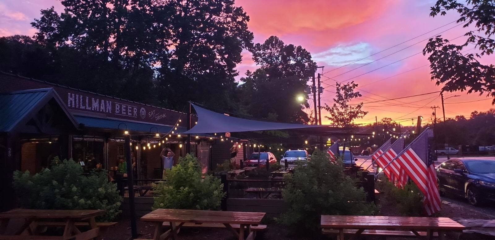 a restaurant exterior at sunset with string lights and flags