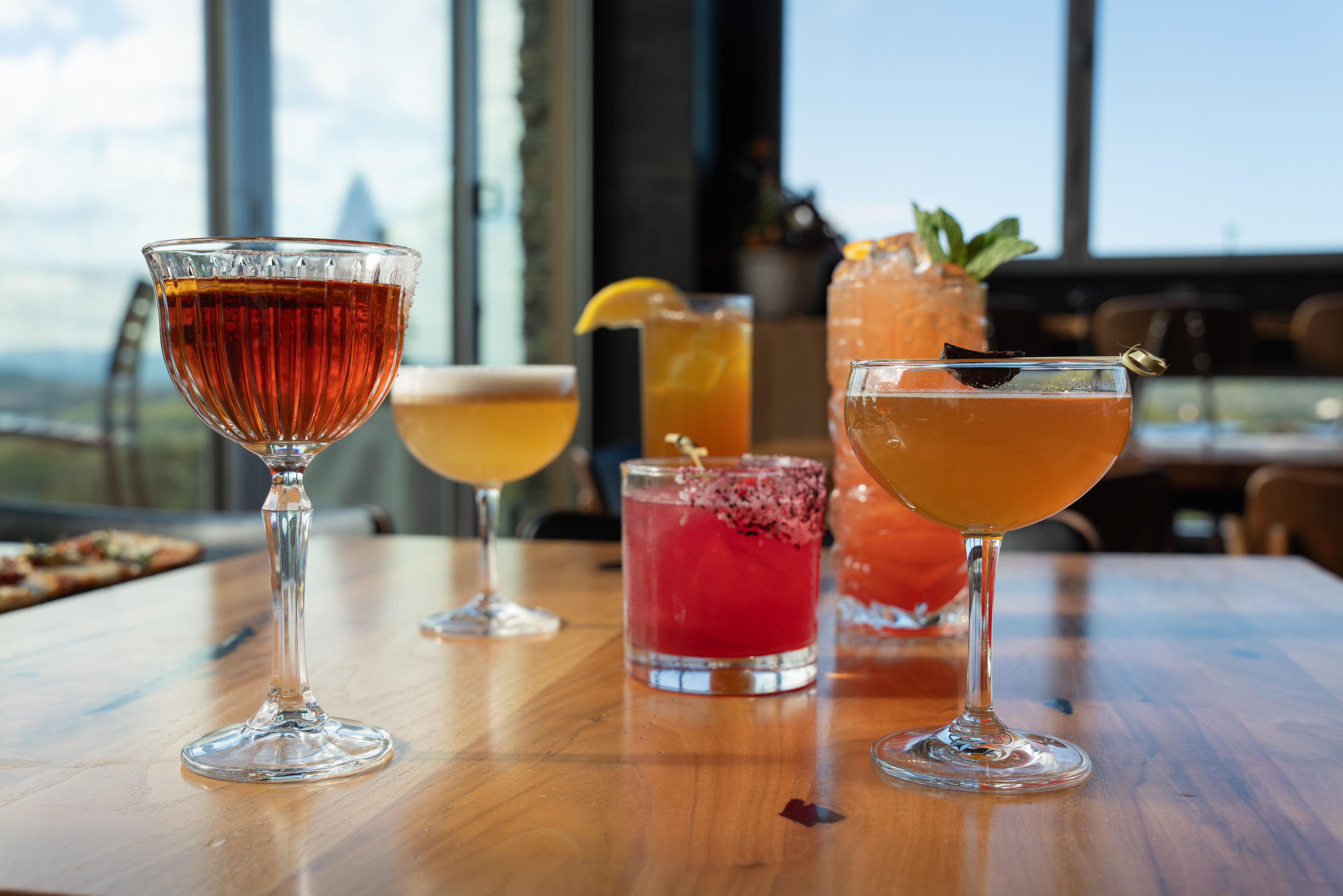 five cocktails on a wooden table
