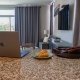 a laptop and leather briefcase sit on the counter with a pastry in between them.